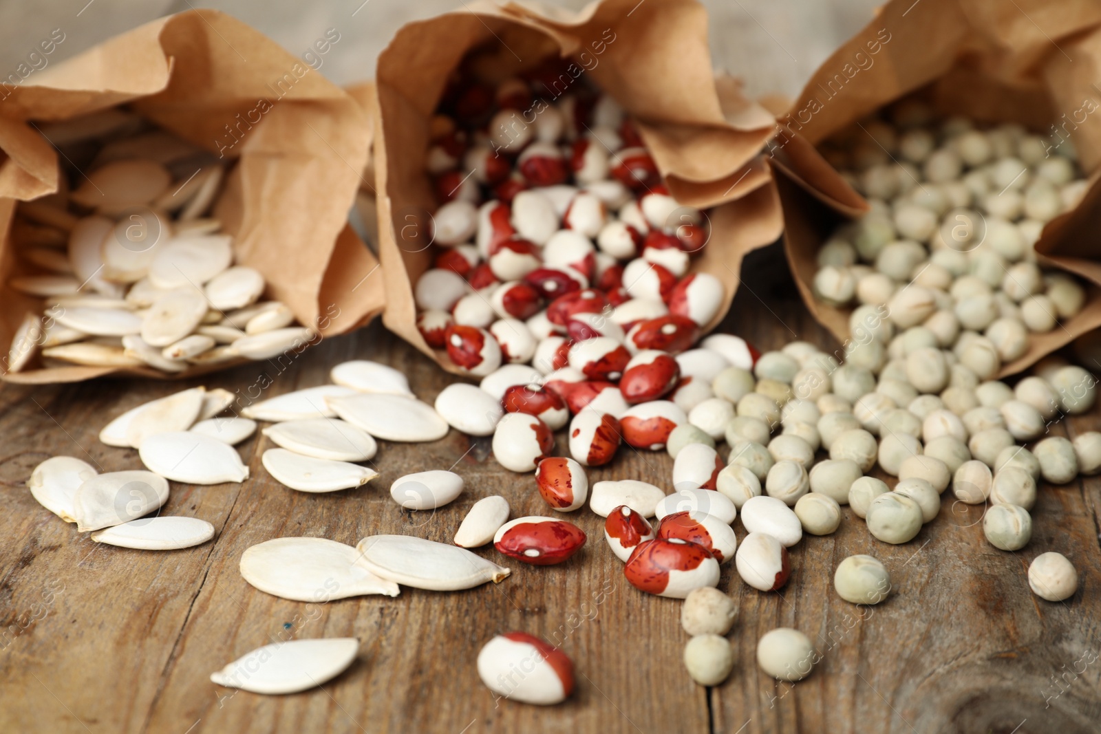 Photo of Different vegetable seeds on wooden table, closeup