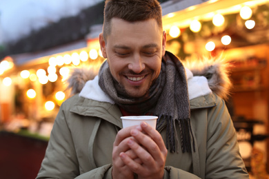 Photo of Happy man with mulled wine at winter fair