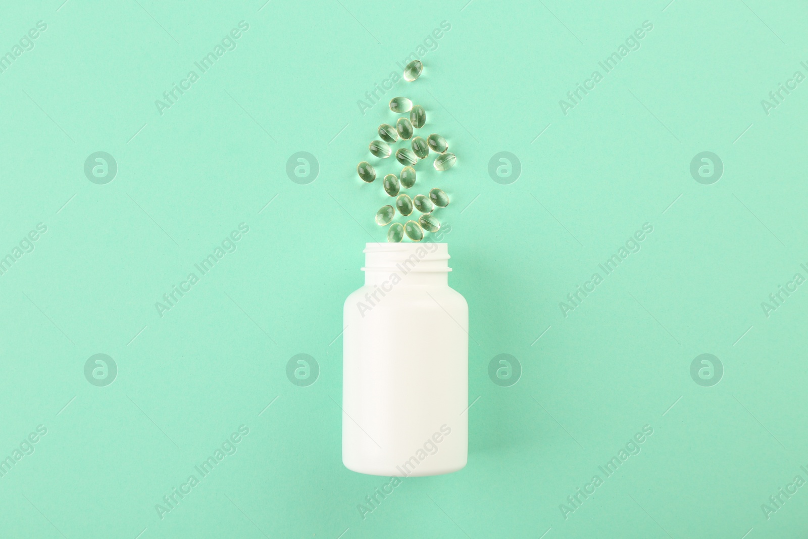 Photo of Bottle and vitamin capsules on turquoise background, top view