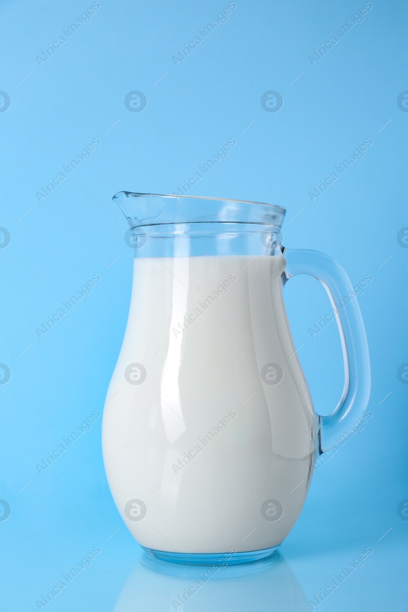 Photo of Jug of fresh milk on light blue background