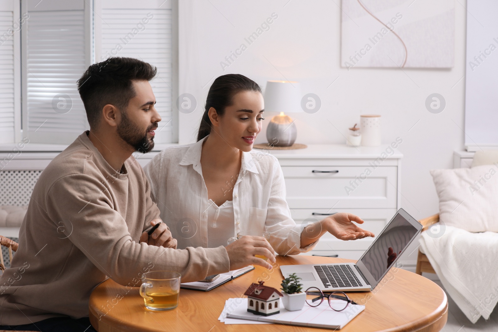 Photo of Happy young couple choosing new house using laptop at home. Mortgage concept