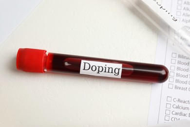 Photo of Test tube with blood sample on white table, flat lay. Doping control