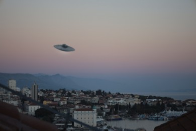 Alien spaceship flying over city in morning. UFO, extraterrestrial visitors