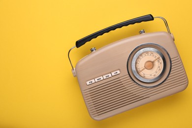 Photo of Retro radio receiver on yellow background, top view. Space for text