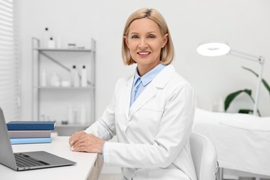 Photo of Portrait of happy dermatologist at white table in clinic