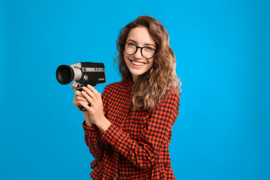 Photo of Beautiful young woman with vintage video camera on light blue background