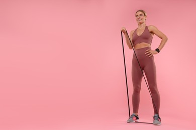 Photo of Woman exercising with elastic resistance band on pink background, low angle view. Space for text