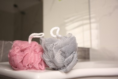 Photo of Colorful shower puffs on washbasin in bathroom, closeup. Space for text