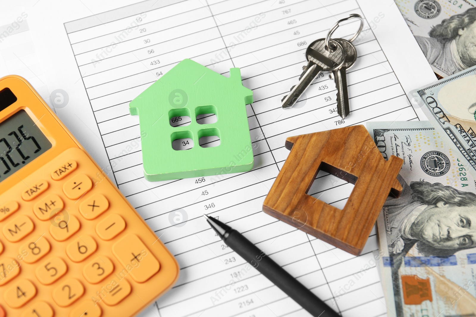 Photo of Calculator, house models, keys and money on documents. Real estate agent's workplace