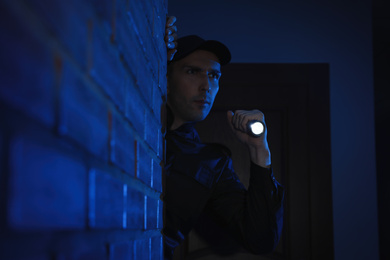 Photo of Male security guard with flashlight in dark corridor