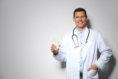 Nutritionist holding glass of pure water on light grey background. Space for text