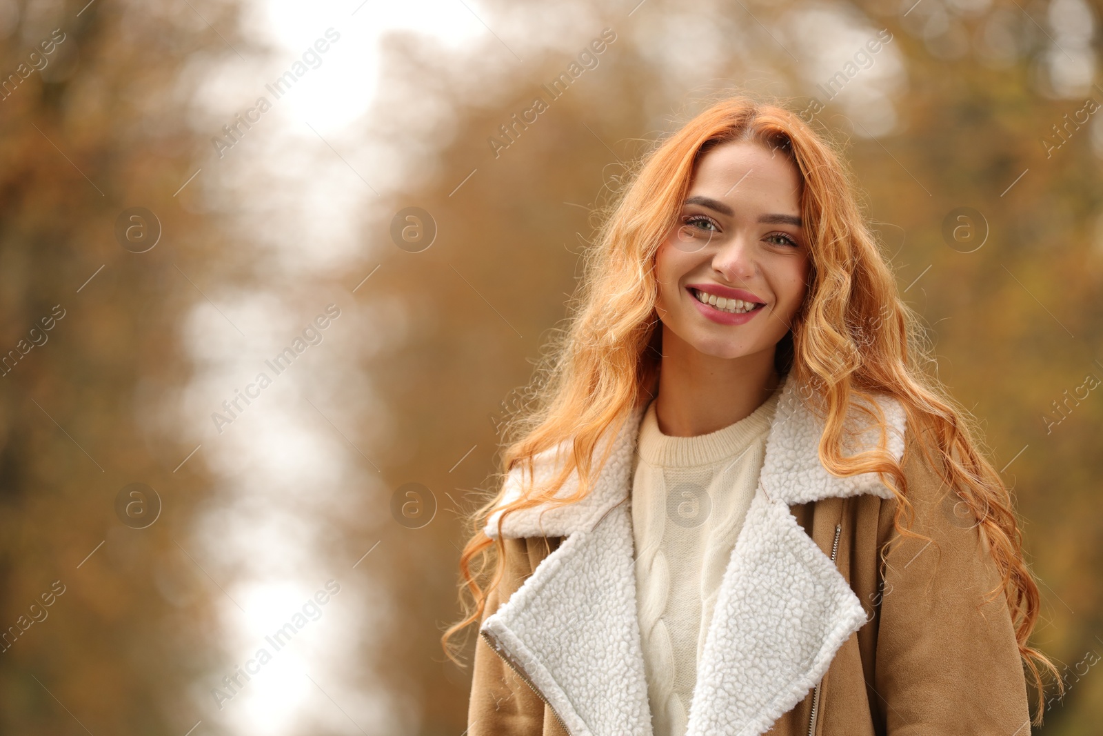 Photo of Autumn vibes. Portrait of smiling woman outdoors. Space for text