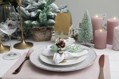 Photo of Festive place setting with beautiful dishware, cutlery and cone for Christmas dinner on white wooden table