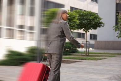 Image of Being late. Woman with suitcase running on city street. Motion blur effect
