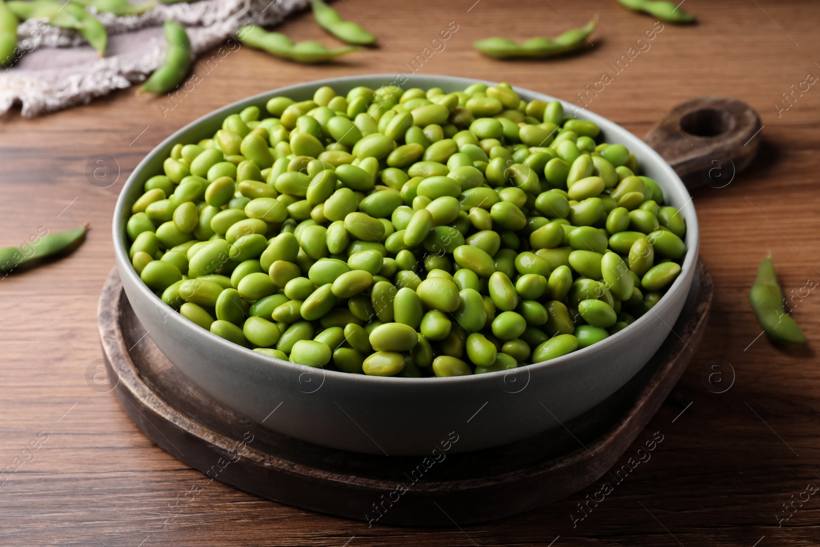 Photo of Bowl of delicious edamame beans on wooden table