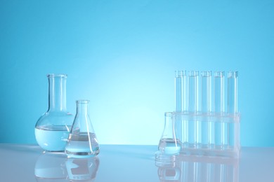 Photo of Laboratory analysis. Glass test tubes and flasks on table against light blue background