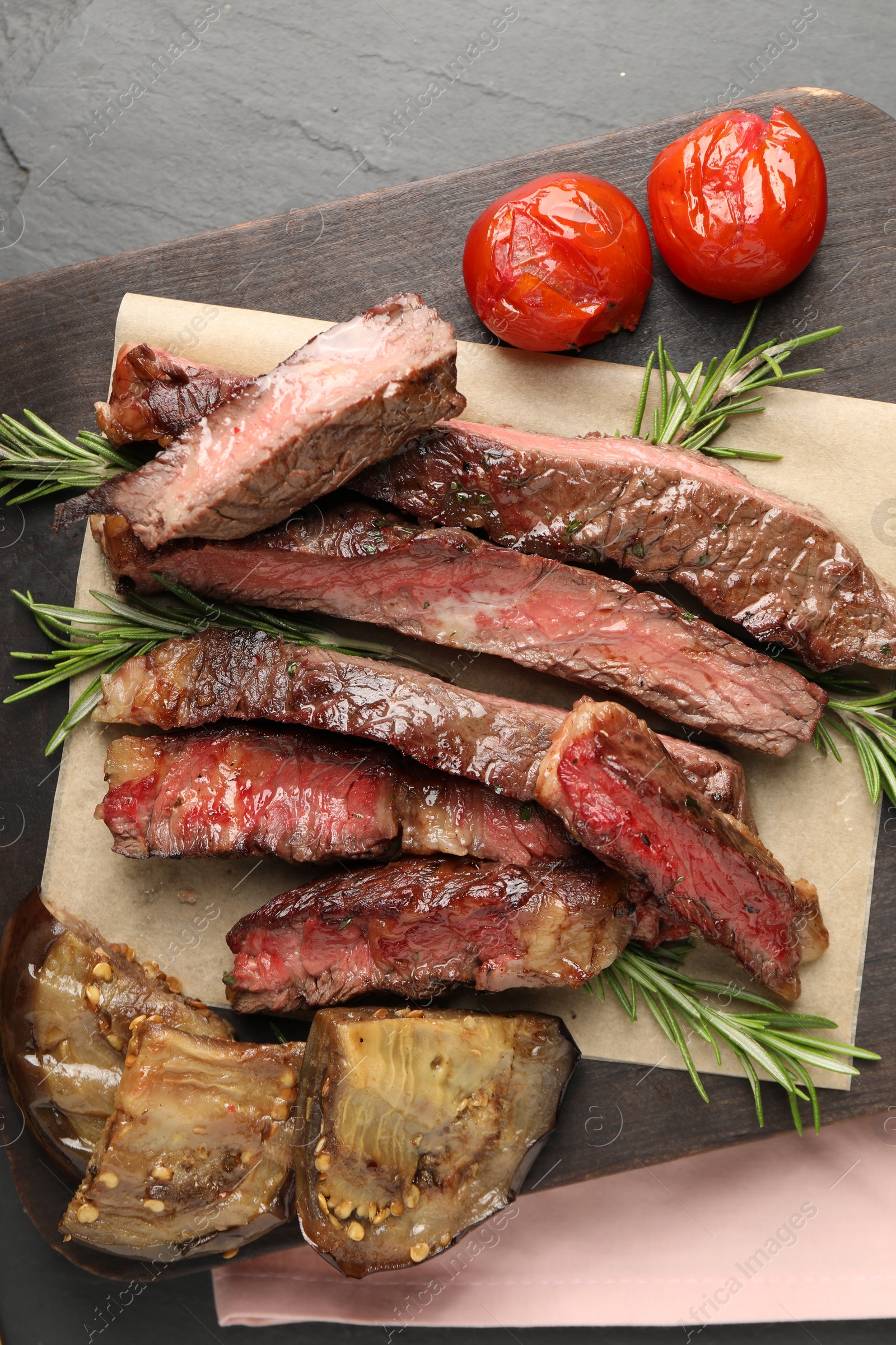 Photo of Delicious grilled beef with tomatoes and rosemary on table, top view