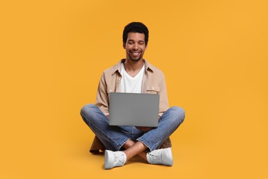 Photo of Happy man using laptop against orange background