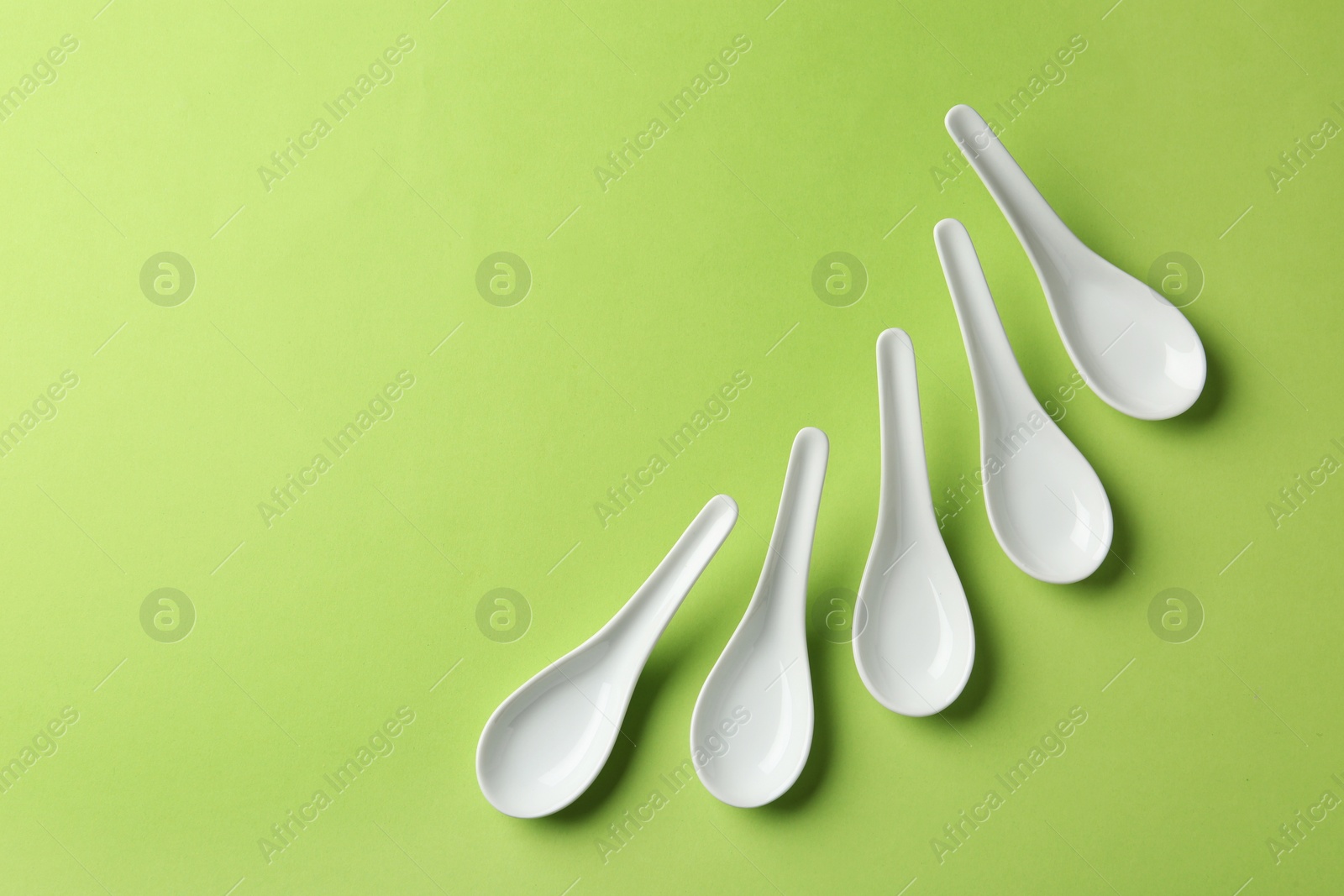 Photo of Miso soup spoons on green background, flat lay. Space for text