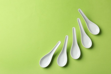 Miso soup spoons on green background, flat lay. Space for text