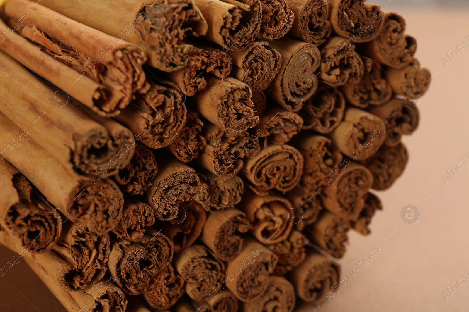 Photo of Aromatic cinnamon sticks on beige background, closeup