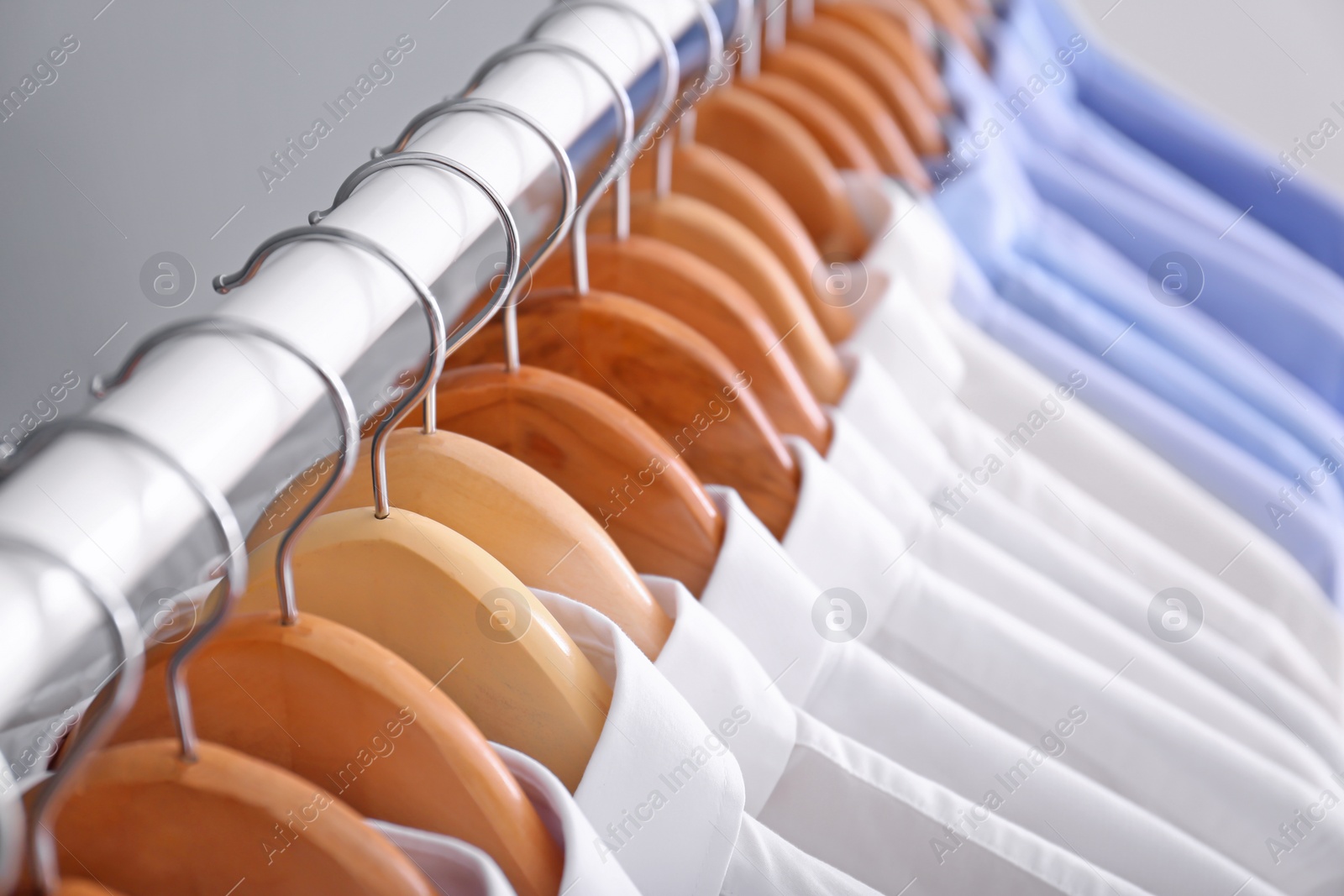 Photo of Rack with clean clothes on hangers after dry-cleaning, closeup