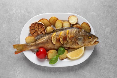 Photo of Tasty homemade roasted perch with garnish on grey table, top view. River fish