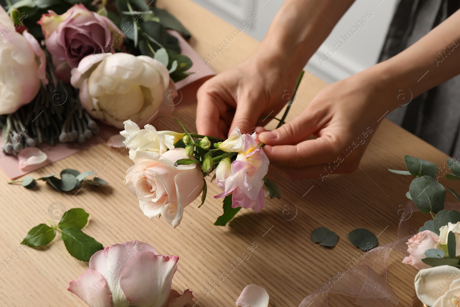 Photo of Florist creating beautiful bouquet at wooden table indoors, closeup