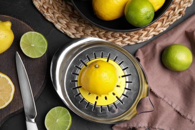 Photo of Squeezer, fresh lemons and limes on black table, flat lay