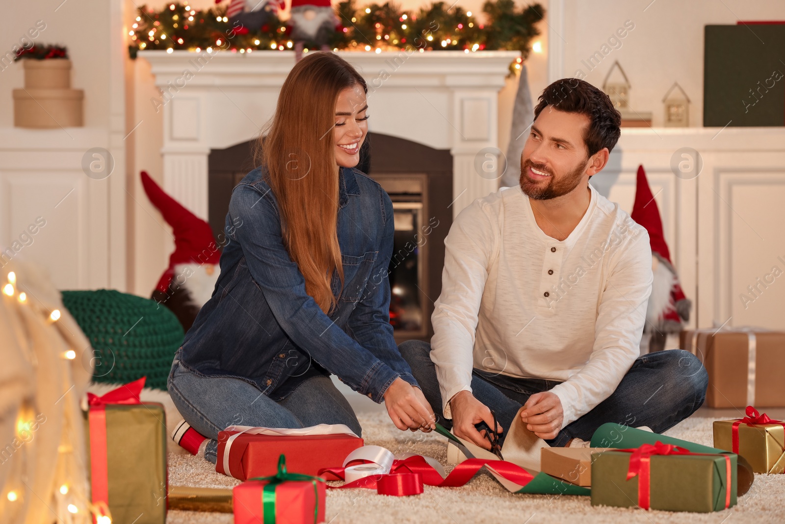 Photo of Happy couple decorating Christmas gifts at home