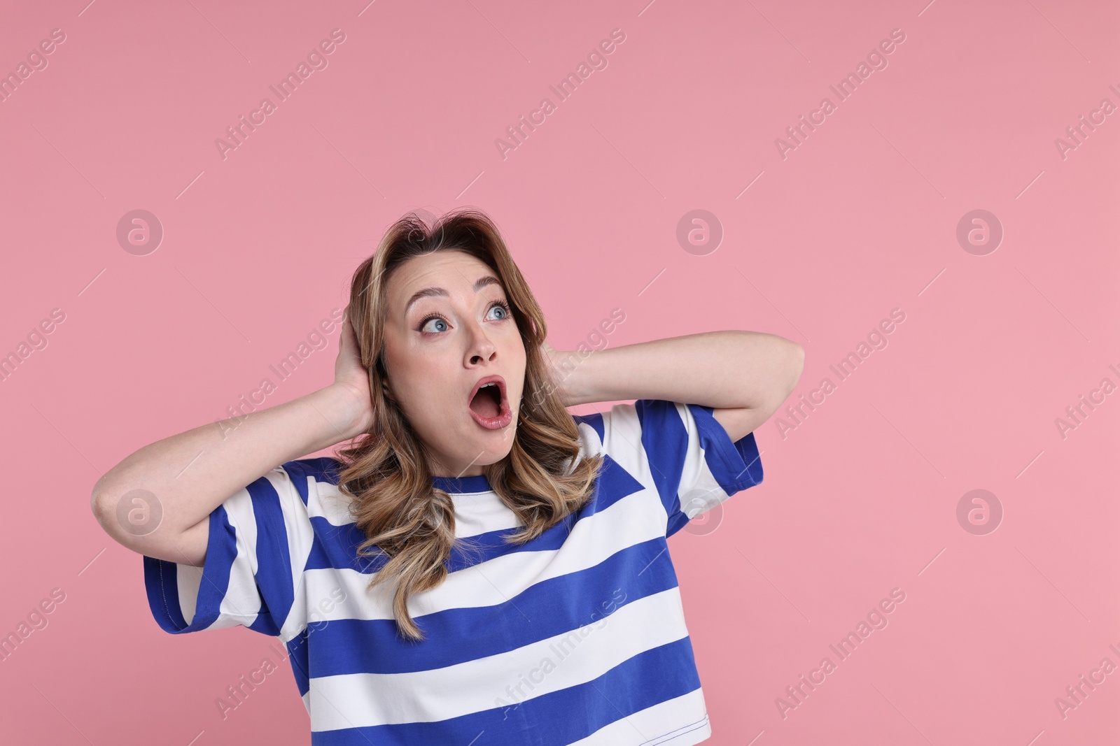 Photo of Portrait of surprised woman on pink background. Space for text