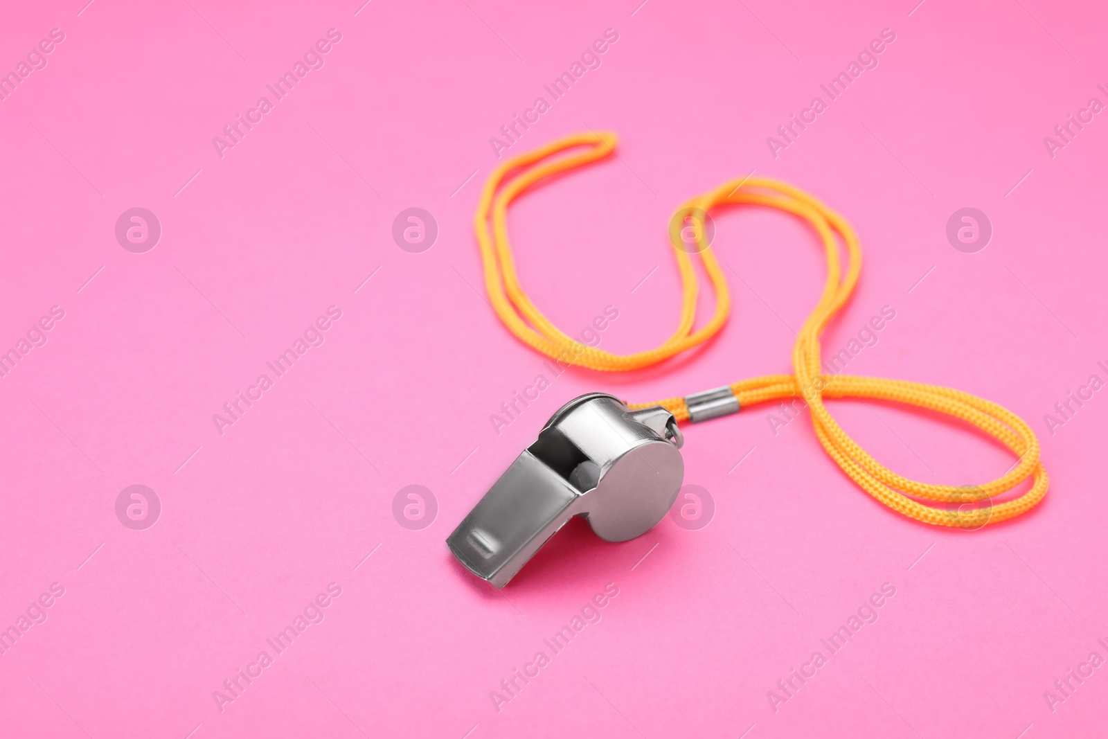 Photo of One metal whistle with cord on pink background