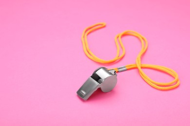 Photo of One metal whistle with cord on pink background