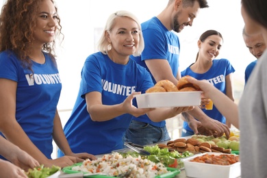 Volunteers serving food to poor people indoors