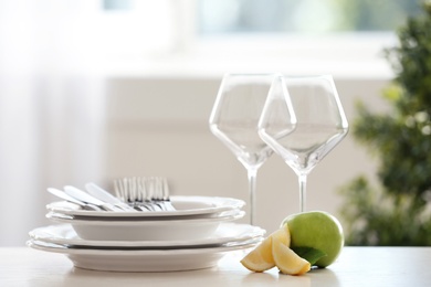 Photo of Set of clean dinnerware and fruits on table indoors