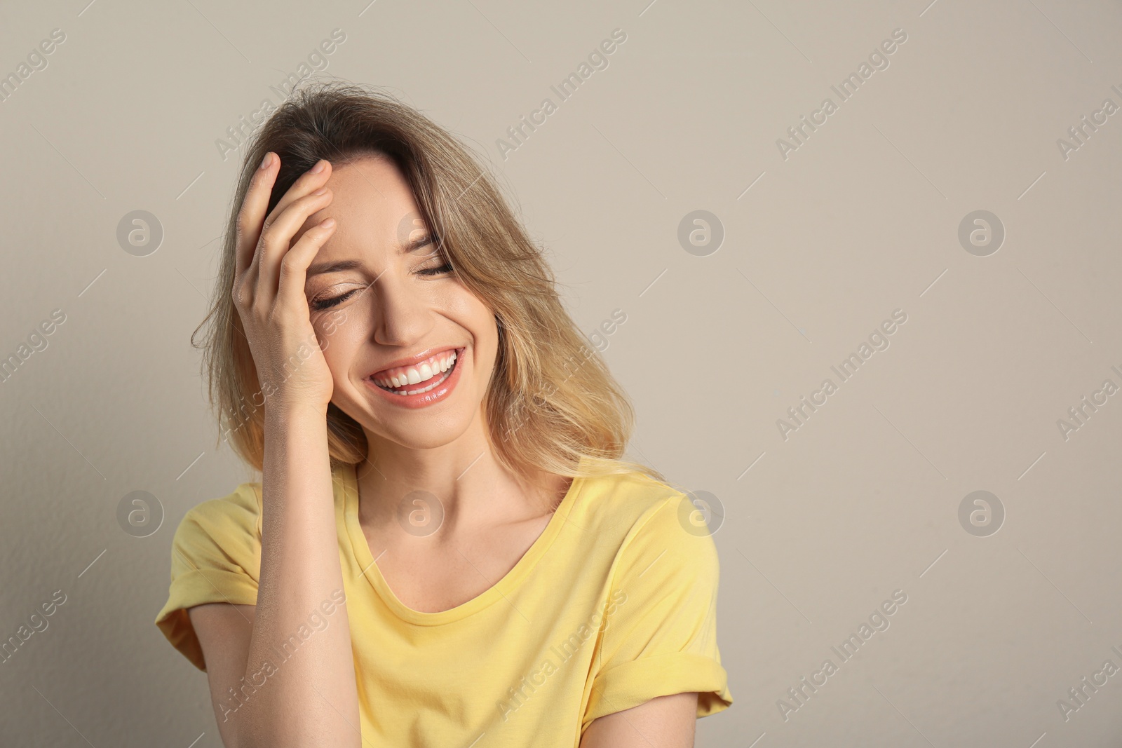 Photo of Portrait of happy young woman with beautiful blonde hair and charming smile on beige background. Space for text