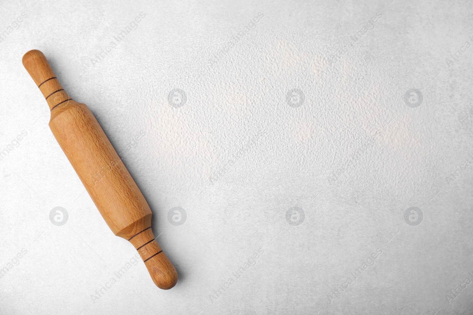 Photo of Rolling pin and flour on light grey table, top view