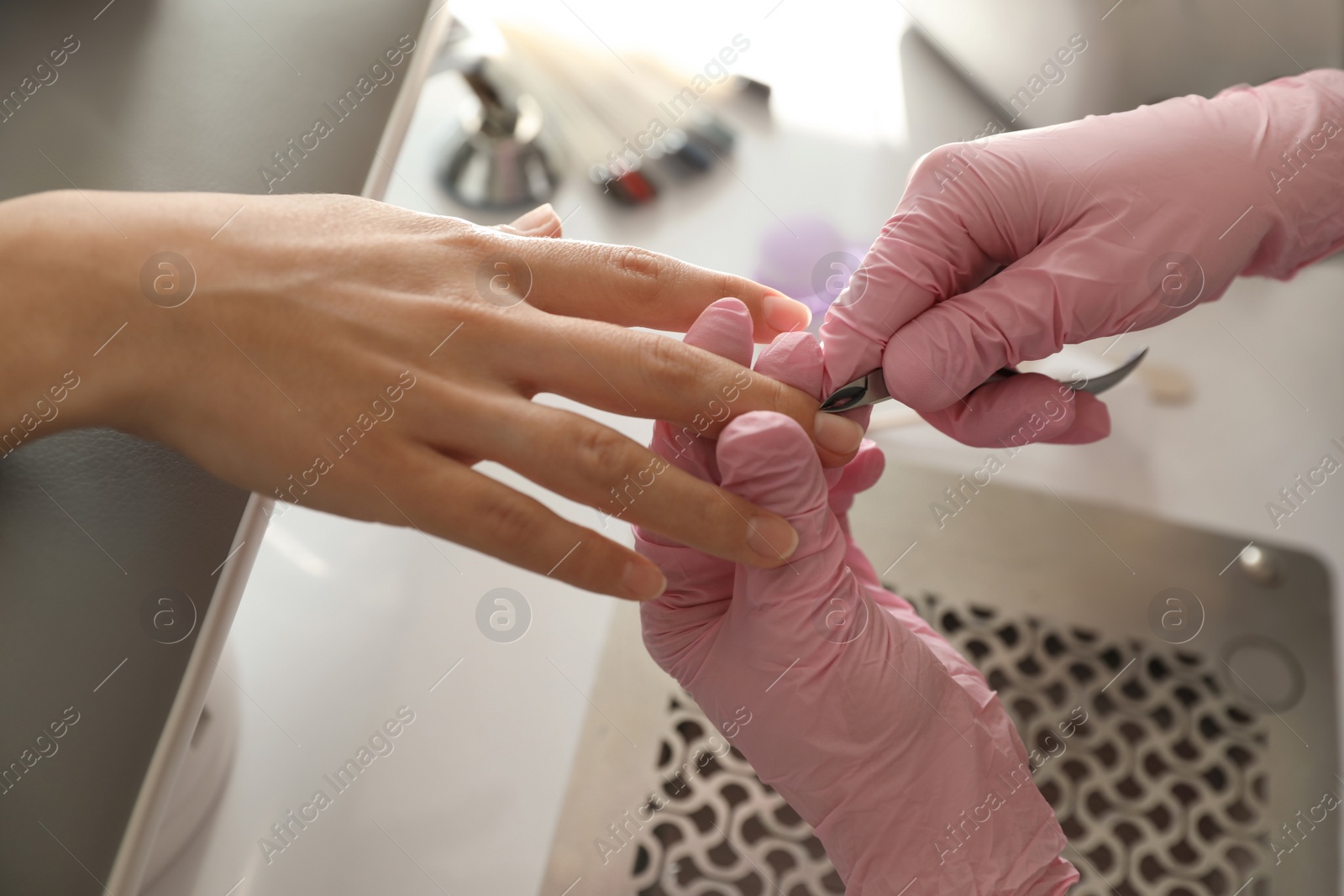 Photo of Professional manicurist working with client in beauty salon, closeup