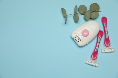 Photo of Epilator, razors and eucalyptus on light blue background, flat lay. Space for text