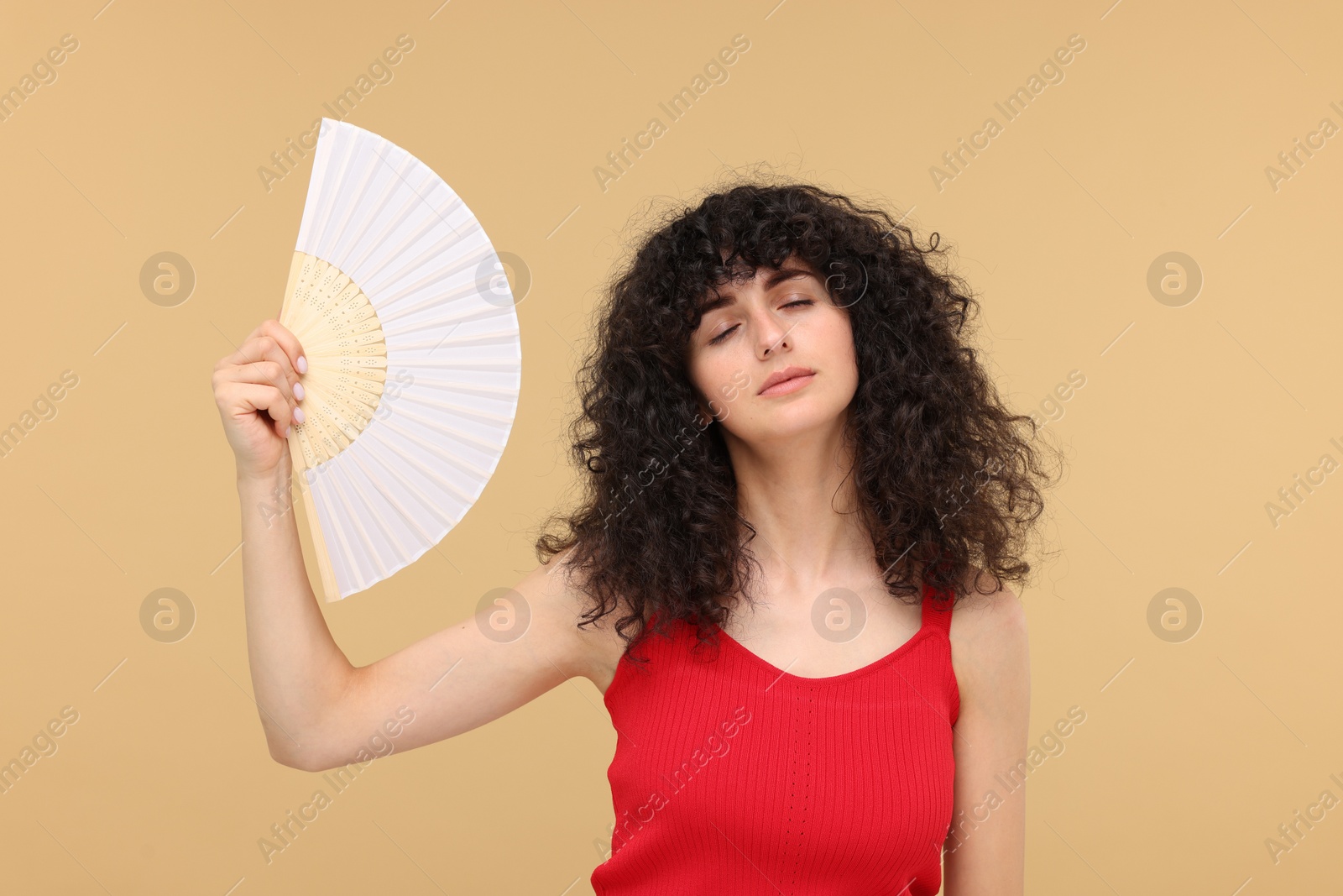 Photo of Woman with hand fan suffering from heat on beige background