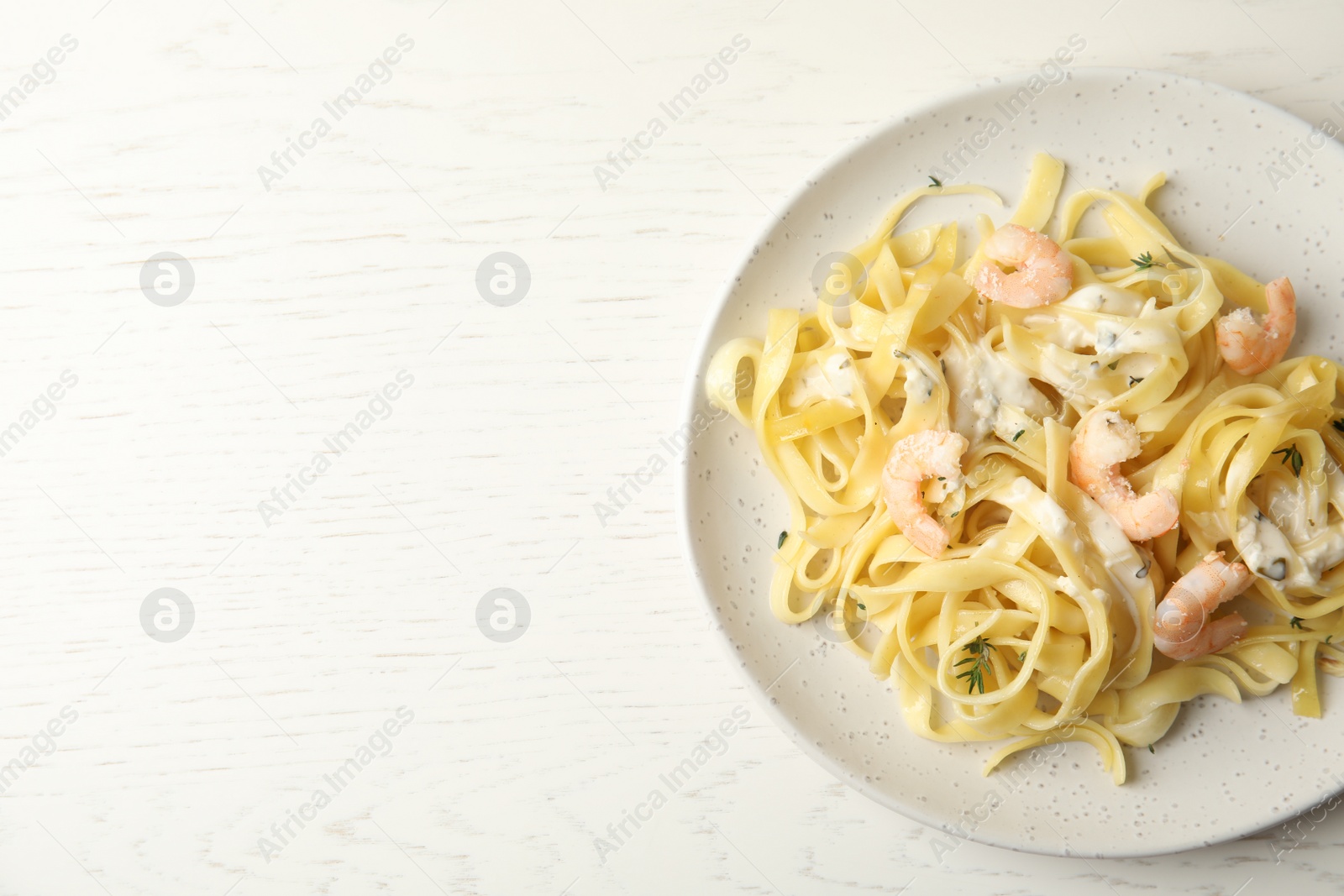 Photo of Delicious pasta with shrimps on white wooden table, top view. Space for text