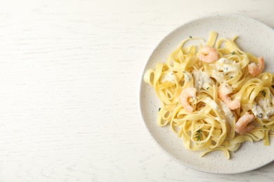 Photo of Delicious pasta with shrimps on white wooden table, top view. Space for text