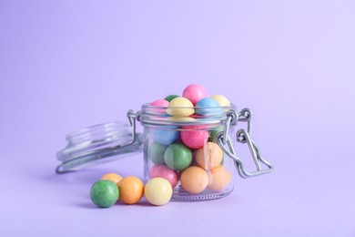 Photo of Jar with many bright gumballs on lilac background