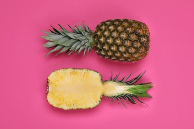 Whole and cut ripe pineapples on pink background, flat lay