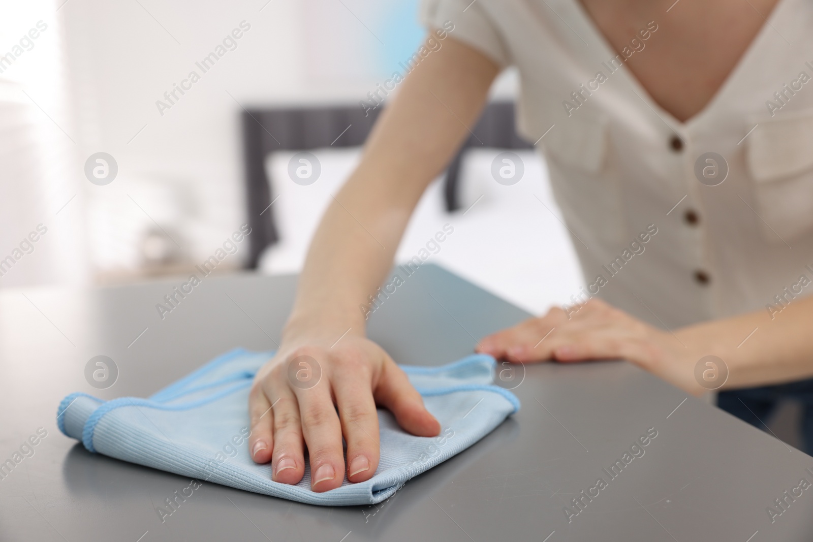 Photo of Woman with microfiber cloth cleaning grey chest of drawers in room, closeup