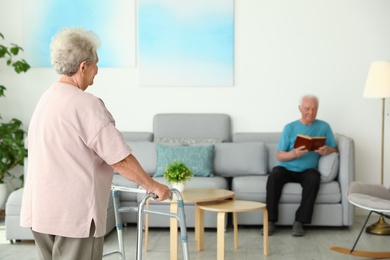Photo of Elderly woman using walking frame and her husband at home