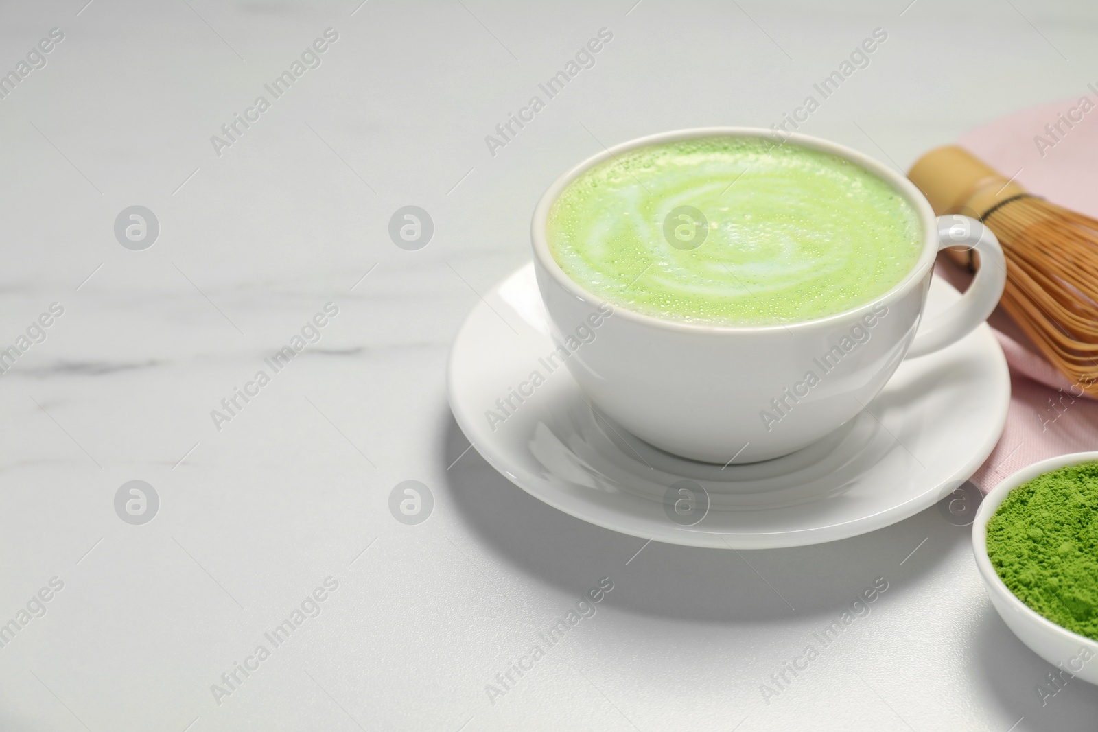 Photo of Cup of fresh matcha latte on white marble table. Space for text