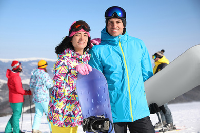 Photo of Couple with snowboards at ski resort. Winter vacation