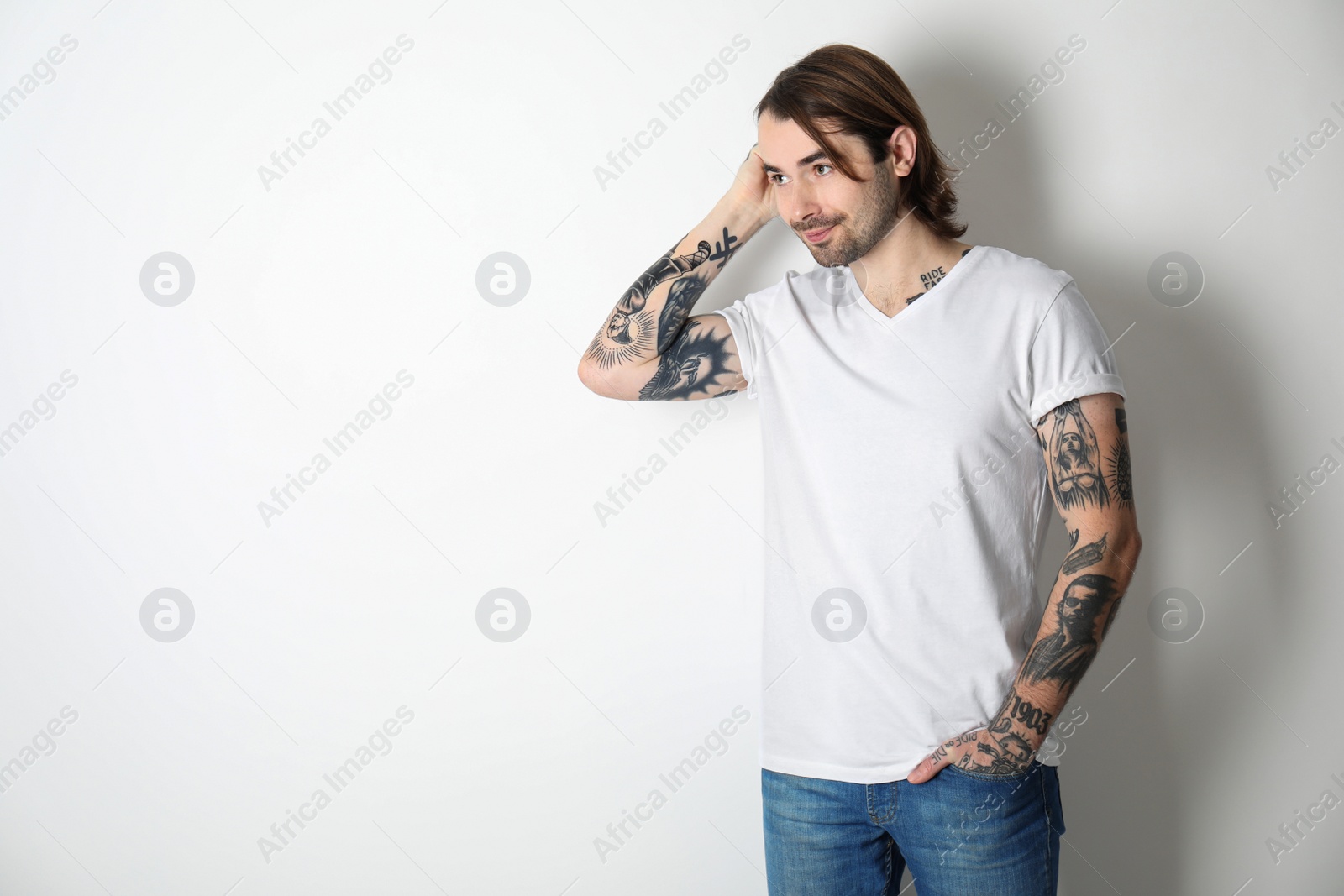 Photo of Young man with tattoos on arms against white background