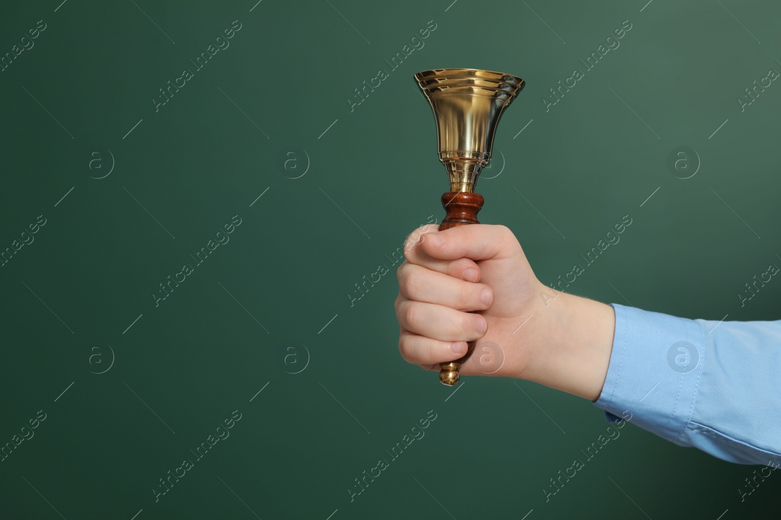 Photo of Pupil with school bell near green chalkboard, closeup. Space for text